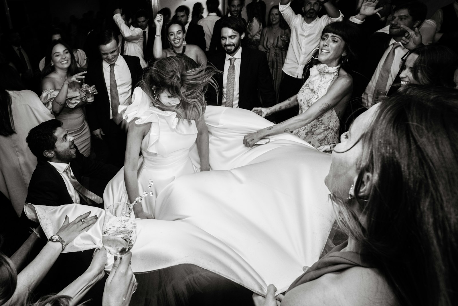Wedding guests lift a bride above a crowded dance floor during a reception dance