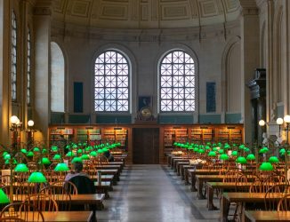 Green reading lamps glowing along the tables of Bates Hall at the Boston Public Library